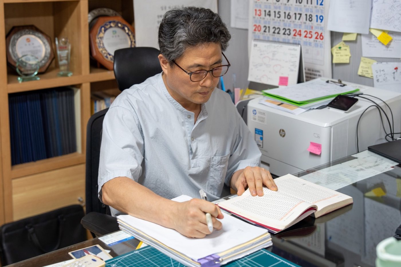 회장 명패가 놓인 책상에서 사주를 적으며 살피는 모습